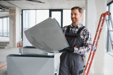 Hvac teknisyeni havalandırma kanalı parçası tutuyor. İnşaat halindeki bir binaya havalandırma sistemi kuruyor.
