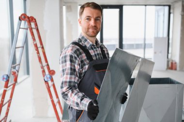 Hvac teknisyeni inşaat halindeki binada kurulum sırasında havalandırma sisteminin metal parçasını taşıyor.