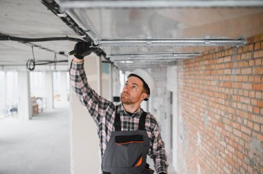 Bir inşaat sahasında havalandırma ve havalandırma sistemi kurulumu üzerinde çalışan bir elektrikçi.