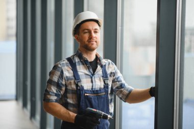 Modern bir binaya cam döşeyen, hassas ölçümler yapan ve enerji verimliliğinin arttırılması ve estetiğin güvence altına alınmasını sağlayan yetenekli işçiler.