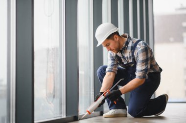 Çağdaş binada hava geçirmez ve enerji tasarruflu kurulum sağlayan, pencere çerçevesine dolgu macunu uygulayan yetenekli işçiler