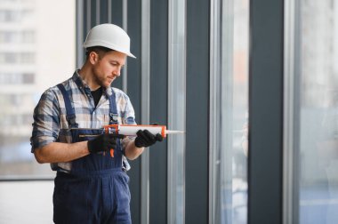 İnşaatçı, inşaat veya yenileme projeleri sırasında hava geçirmez ve hava geçirmez kurulum sağlayan bir pencere çerçevesine dolgu macunu uyguluyor
