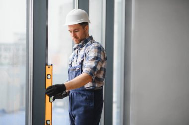 İnşaat halindeki binada pencere kurulumu sırasında ruh seviyesini tam olarak ayarlayarak inşa eden kişi