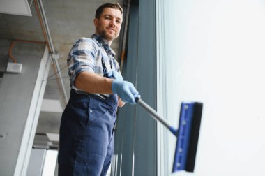 Cam sileceği kullanarak cam sileceği kullanarak şık, modern bir ofis binasının camlarını titizlikle temizliyor.