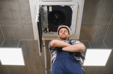 Modern ofis binasında kurulum sırasında klima altında kolları çapraz duran kendinden emin Hvac teknisyeni.