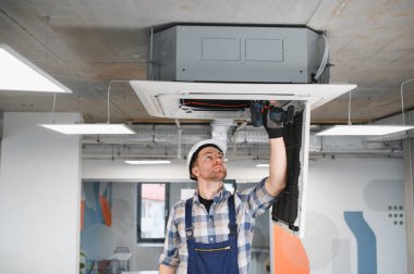 Ofis binasına klima kurarken kablosuz tornavida kullanan Hvac teknisyeni