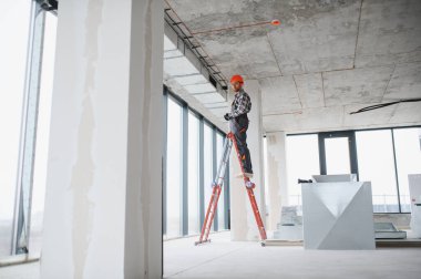 İnşaat işçisi inşaat halindeki bir binaya havalandırma sistemi kurarak düzgün bir hava akımı ve rahat bir ortam sağlıyor.