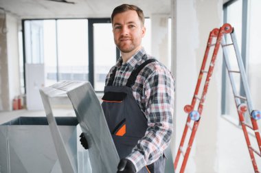 Havalandırma sistemi kurulumu sırasında inşaat halindeki bir binada metal havalandırma kanalı montajı yapan Hvac teknisyeni