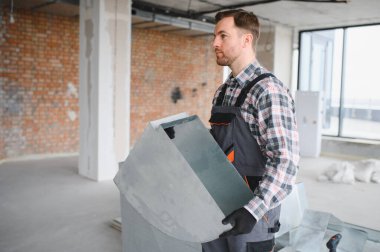 Bir bina yenileme projesinde çalışırken havalandırma boruları taşıyan inşaat işçisi, verimli bir hvac sistem kurulumunu garanti altına alıyor