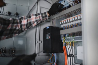 Güvenlik kaskı takan elektrikçi inşaat halindeki bir binanın elektrik panelinde çalışıyor.