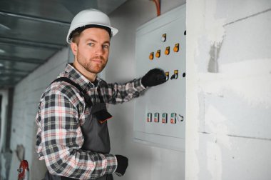 İnşaat sırasında elektrik panelinde çalışan yetenekli elektrikçi güvenlik ve uygun elektrik sistemi kurulumunu sağlıyor.