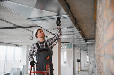 Hvac teknisyenleri işlek bir şantiyeye havalandırma ve havalandırma boruları kurarak modern binaların verimli hava akışını sağlıyorlar.