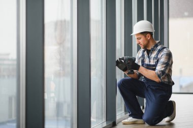 Modern bir binaya cam döşeyen, hassas ölçümler sağlayan ve optimal enerji verimliliği ve yapısal bütünlük için güvenli bir düzenleme sağlayan yetenekli işçiler.