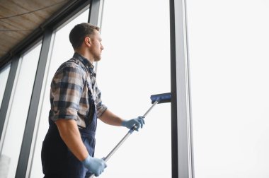 Modern bir ofis binasının camlarını silmek için cam temizleyicisi kullanıyor. Pırıl pırıl parlıyor.