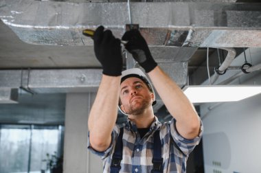 Hvac teknisyenleri havalandırma sistemi kanallarını kurarken ya da tamir ederken vidaları sıkıyor, uygun hava akışını sağlıyor ve kapalı alanda rahat bir ortam sağlıyor