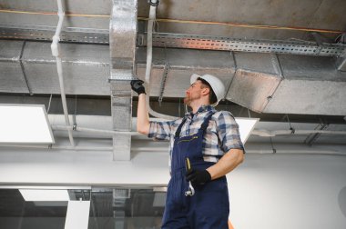 Hvac teknisyeni, ticari binada inşaat ve onarım sırasında havalandırma sistemini kontrol ediyor.
