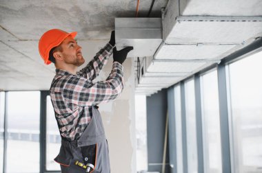 Miğfer takan inşaatçı, bir inşaat veya yenileme projesi sırasında havalandırma boruları kurarak uygun hava akışını ve sistem verimliliğini sağlıyor