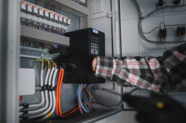 Güvenlik kaskı takan elektrikçi inşaat halindeki bir binanın elektrik panelinde çalışıyor.