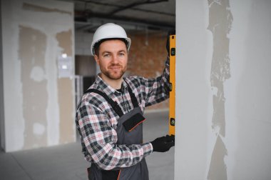 İnşaat işçisi bina yenileme sırasında ruh seviyesini kullanarak duvarın dikeyliğini kontrol ediyor