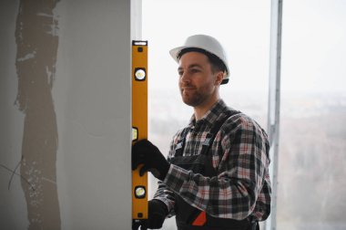 İnşaat sırasında duvarın dikey hizalanmasını kontrol etmek için ruh seviyesini kullanan inşaatçı, bölgede hassasiyet ve doğruluğu sağlama alıyor