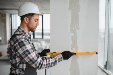 İnşaat veya yenileme projesinde duvar onarımı sırasında ruh seviyesini kullanarak tam bir dikey hizalama sağlar