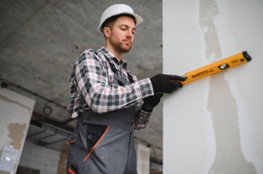 Bir bina yenileme projesinde duvar inşaatı sırasında ruhsal seviye kullanan inşaatçı kesin olarak dikey hizalama sağlar