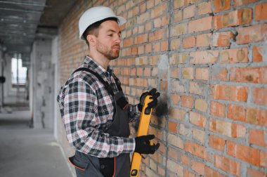 İnşaatçı inşaat sırasında ruhsal seviyesini kullanarak inşaat başlığı ve tulum giyer, doğru ve hassas bir yapı sağlar.