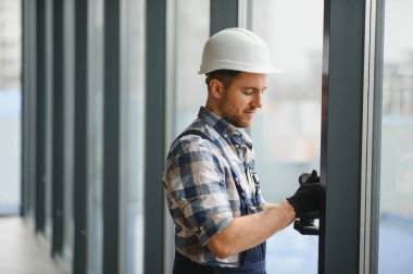 Modern bir binaya cam döşeyen yetenekli işçiler, hassas ölçümler ve optimal enerji verimliliği ve yapısal bütünlük için güvenli donanımlar sağlıyorlar.