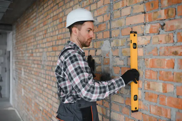 Ruh seviyesini kullanan inşaatçı tuğla döşeme sırasında hassas bir hizalama sağlar, inşaat kalitesinde doğruluk ve kalite vurgulanır