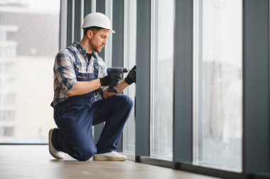Elektrikli matkap kullanan usta işçiler, inşaat halindeki modern bir binaya pencere döşemek, hassas ve güvenli bir yer temin etmek,