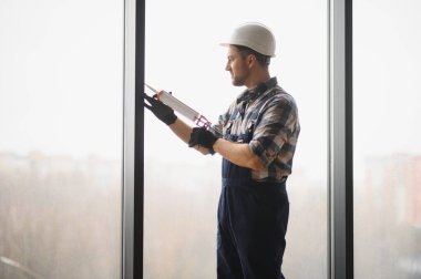 İnşaatçı pencere kurulumu sırasında dolgu tabancası kullanarak hava geçirmez mühür ve enerji verimliliği sağlıyor