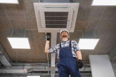 Hvac teknisyeni bir binada havalandırma ve iklim kontrolü sağlamak için havalandırma ünitesi kurulumu üzerinde çalışıyor.