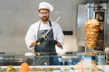 Aşçı keskinleştirme büyük bıçak hazırlamak ticari mutfakta donör kebap et kesmek için çeşitli malzemeler ön planda sergilenmektedir