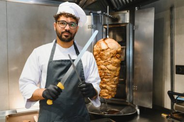 Profesyonel aşçı bıçakları biliyor, ticari bir mutfakta lezzetli bir shawarma hazırlıyor.