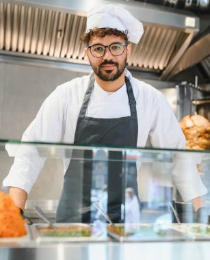 Üniformalı, gözlüklü, kendine güvenen Arap aşçı sokak yemeği kamyonunda kebap ve shawarma hazırlıyor.