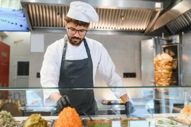 Profesyonel şef shawarma ya da kebap için malzeme hazırlıyor, fast food restoranında taze sebze ve soslar hazırlıyor.
