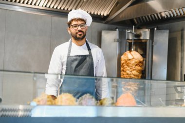 Orta Doğulu şef canlı, modern bir sokak yemeği restoranında ağız sulandıran shawarma 'yı ustalıkla hazırlıyor.