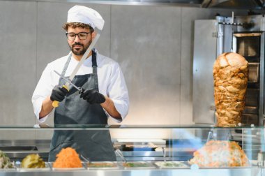 Fast food restoranında donör kebabı dilimleyip lezzetli sokak yemekleri yapmaya hazırlanırken yemek pişirmek.