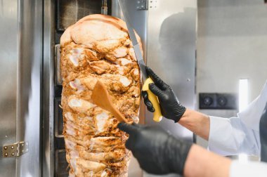 Dikey bir rostodan dilimlenmiş eti pişirip geleneksel bir orta doğu yemeği yapmak.