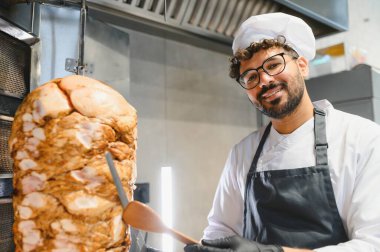 Lezzetli shawarma hazırlamak geleneksel yöntemlerle, profesyonel mutfakta dönen tükürükten baharatlı et dilimlemek.