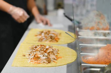 Doğu mutfağındaki bir fast food restoranında kebap ya da shawarma hazırlamak için lavaşın üzerine tavuk ve sebze ekliyorum.