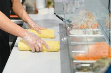 Aşçı, fast food restoranında taze malzemelerle iki paket yapar. Hijyen için plastik eldiven kullanır.