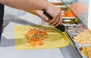 Aşçı lahanalı lahanaya salatalık ve havuç ekliyor, fast food restoranında shawarma ya da kebap hazırlıyor.