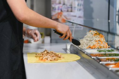 Şavurma ya da kebap 'a tavuk ve sebze eklemek için bir fast food restoranında maşa kullanmak şark mutfağında uzmanlaşmak.