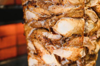 Lezzetli tavuk shawarma dikey bir tükürük üzerinde dönüyor, yavaşça pişiyor ve gevrek oluyor, pide veya diğer düz ekmeklerde servis edilmeye hazır.