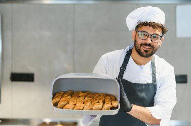 Gülümseyen şef lezzetli baklava hamur işleri sunuyor, Orta Doğu ya da Akdeniz mutfağında uzmanlık gösteriyor