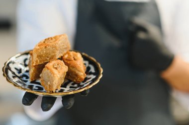 Süslü bir tabakta eldivenli eller Orta Doğu ya da Akdeniz mutfağını gözler önüne seriyor.