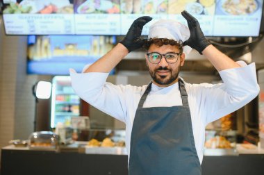 Orta Doğulu aşçı hamburgerciyi bir fast food restoranında ayarlıyor. Lezzetli kebap ve shawarmas hazırlamaya hazır.