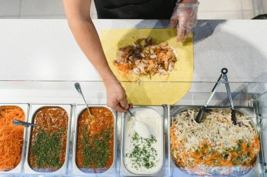 Etli, sebzeli ve soslu leziz bir shawarma ya da kebap hazırlayıp, kaşıkla beyaz sarımsak sosu ekliyorum.