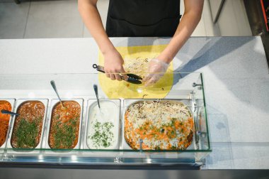 Pide ekmeğine lahana eklemek, maşa kullanmak ve eldiven giymek, yakınlarda soslar ve sebzeler, lezzetli sokak yemekleri yapmak.